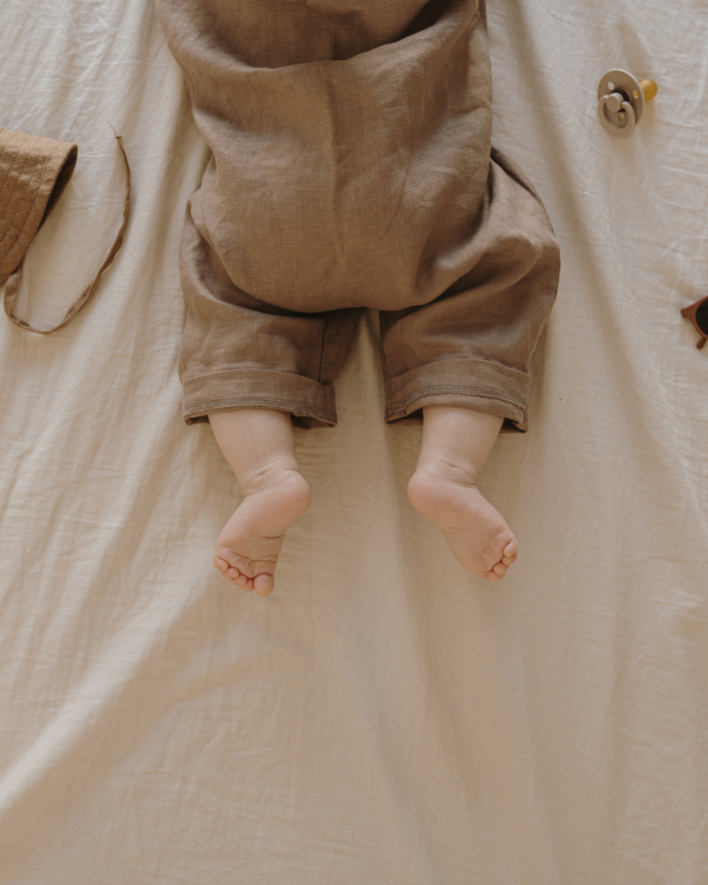 A baby's bare feet on a linen blanket